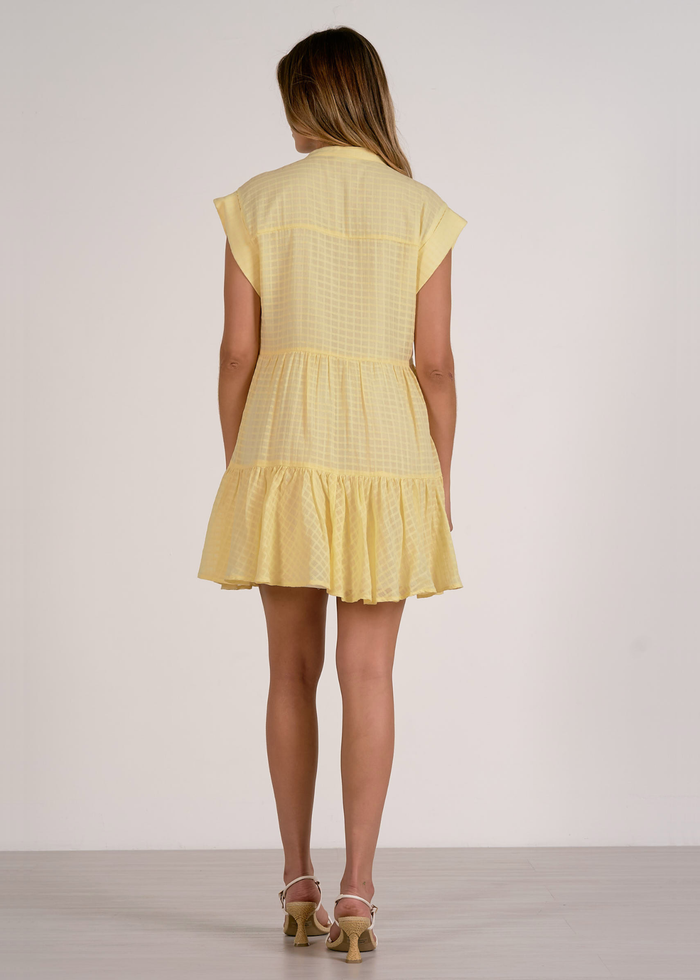 Woman turned around wearing a yellow mini dress
