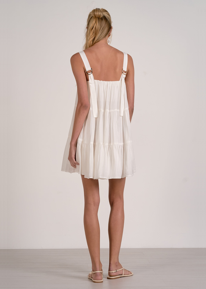 Woman turned around wearing a white tiered mini dress with sandals