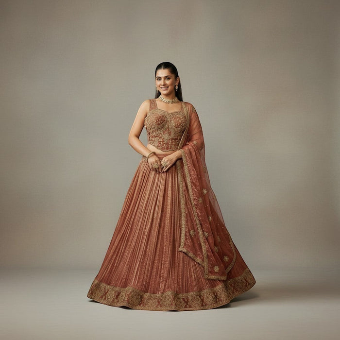 Kurti Connection USA embroidered lehenga set in warm rust with gold detailing. Sleeveless blouse and flowing pleated skirt.
