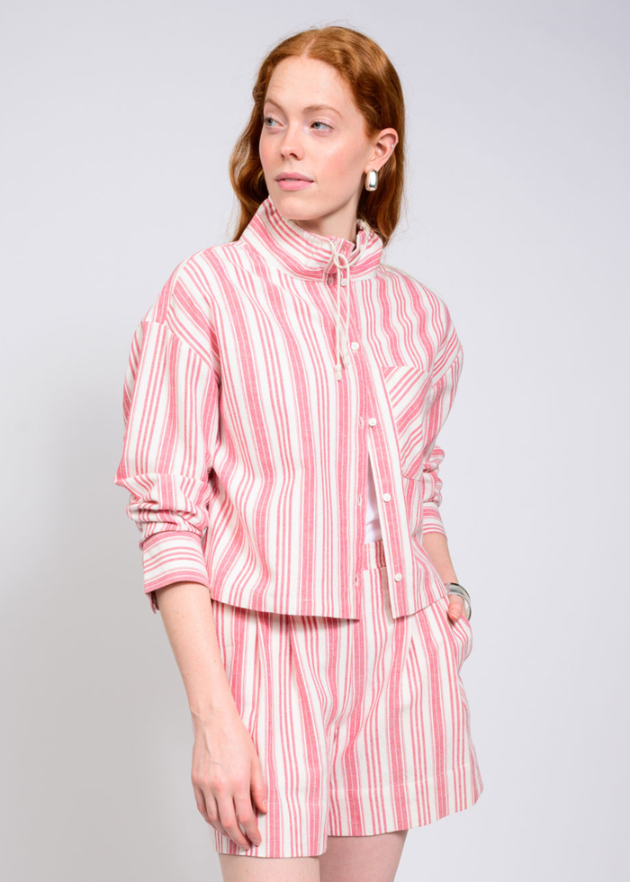 Woman wearing a mock neck and 3/4 length sleeve pink and white striped top with matching shorts