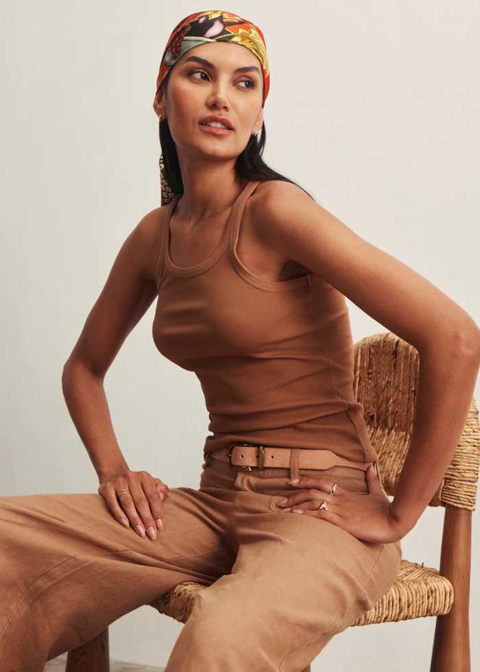 Woman sitting in a chair wearing brown wide leg pants with a brown tank top