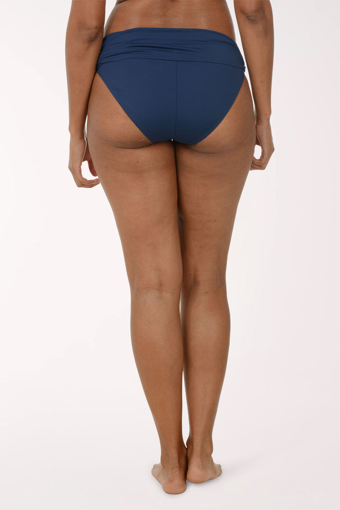 Person wearing a navy blue swimsuit bottom on a white background