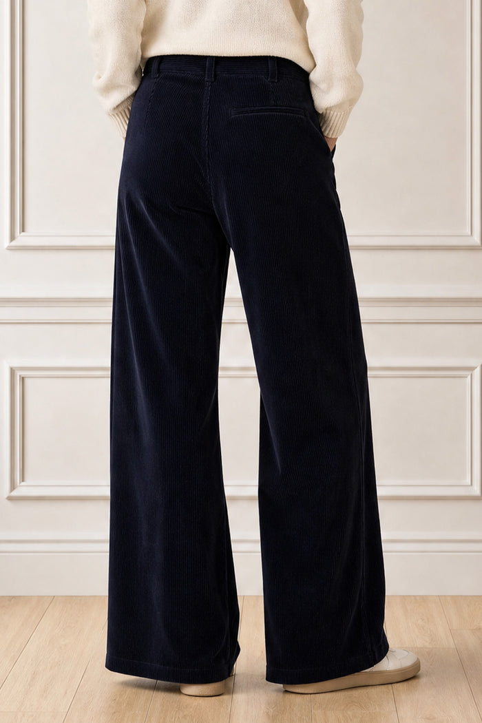 Model wearing the Aspiga Wide Leg Chunky Corduroy Trouser in Deep Navy with a cream jumper, back view