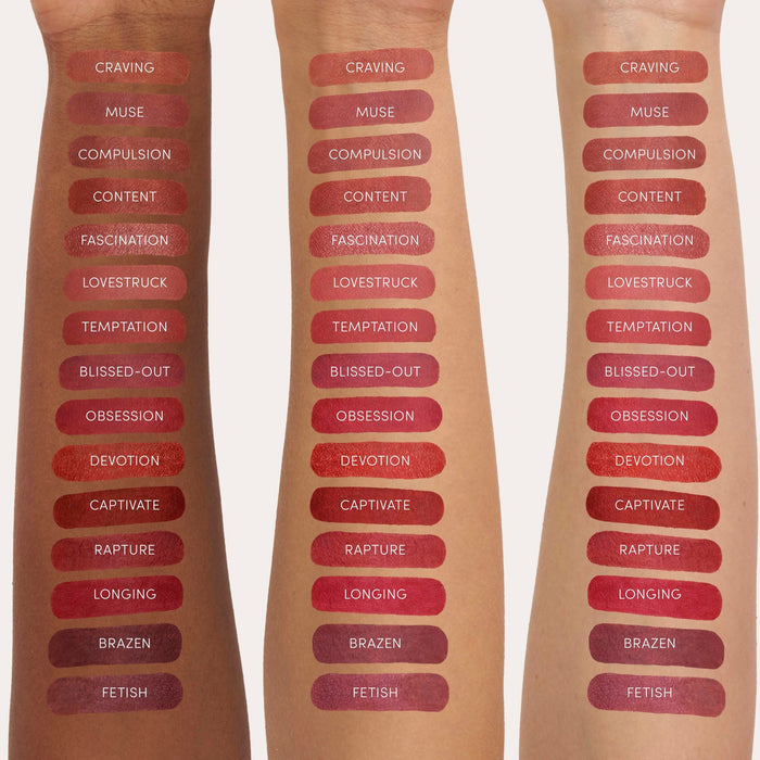 Three arms with multiple swatches of lip stain shades ranging from deep reds to warm browns, each labeled with names like Craving, Muse, and Devotion, showcasing Beyond Matte® Lip Stain | Jane Iredale colors on diverse skin tones.