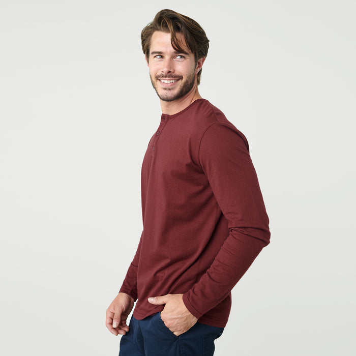 Man wearing Burgundy Classic Long Sleeve Henley, smiling slightly, hand in pocket.