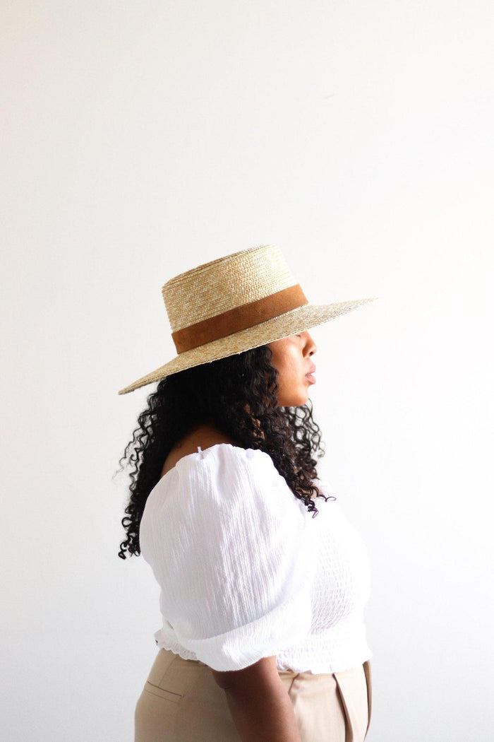 Woman wearing a straw hat with a brown band on a white background