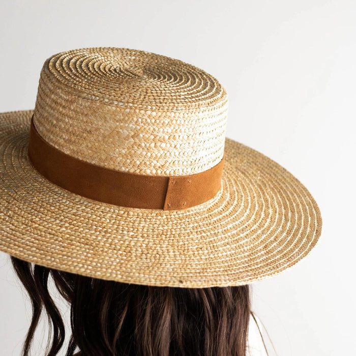 Straw hat with a brown band on a neutral background