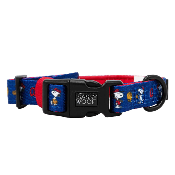 The Sassy Woof Dog Collar - MLB™ x Peanuts™ Atlanta Braves™ features blue and red designs with cartoon Snoopy, a black Sassy Woof buckle, and a metal ring for leash attachment.