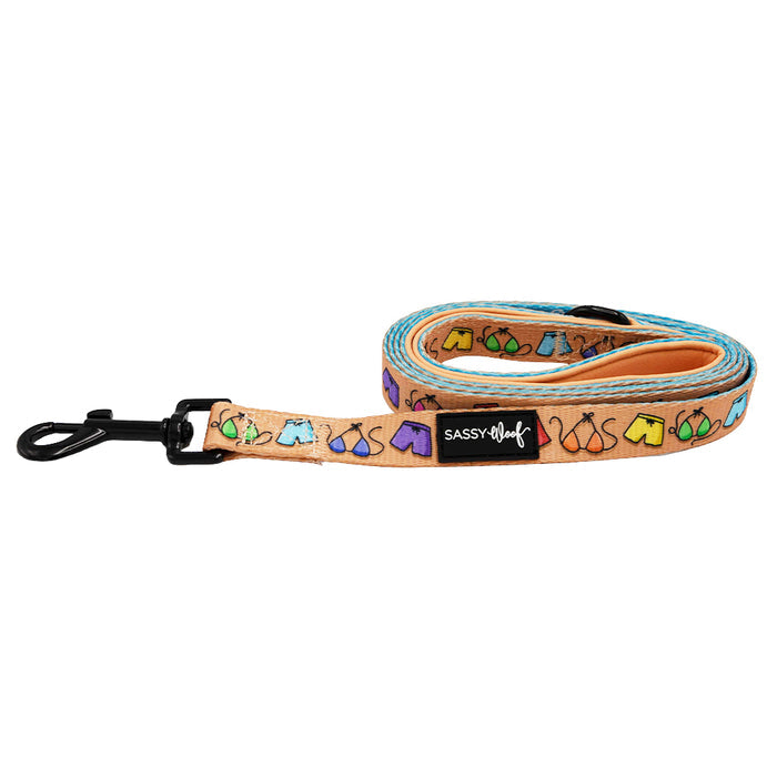 The Sassy Woof Dog Leash - Beach Bod is peach-colored with colorful tent prints, a black metal clasp, brand tag, and a comfy neoprene handle.