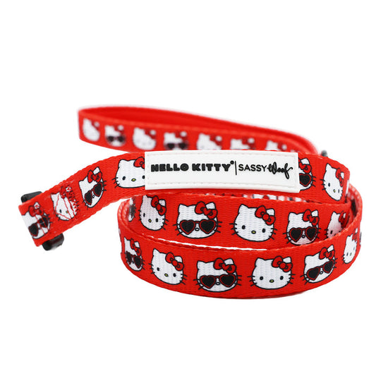 The Dog Leash - Hello Kitty® Red Classic by Sassy Woof features repeating Hello Kitty faces, some with sunglasses, and a white label with HELLO KITTY | Sassy Woof text—perfect for completing your Sanrio accessories set.