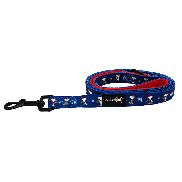 The Sassy Woof Dog Leash - MLB™ x Peanuts™ New York Yankees™ features a blue design with Snoopy and Yankees logos, a black clasp, a black Sassy Woof label on the handle, and a red inner side.