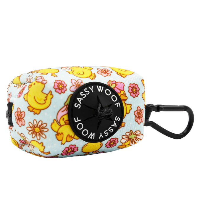 The Sassy Woof Dog Waste Bag Holder - Good Duck, Babe! features a floral and yellow duck pattern, a black "Sassy Woof" label, and clip—perfect to pair with matching dog harness or other duck-themed accessories.