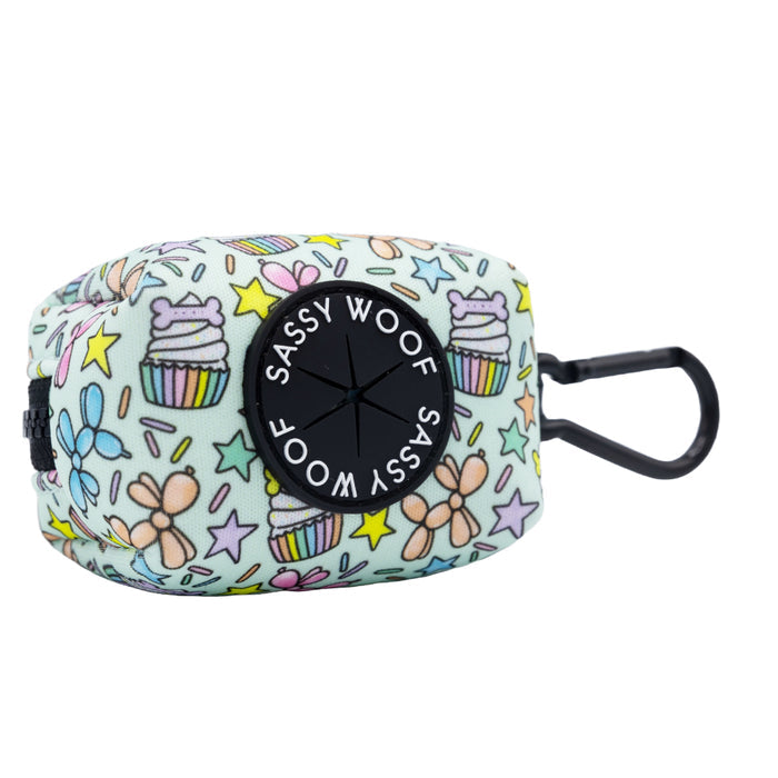 The Sassy Woof Dog Waste Bag Holder - Pup Pup Hooray is a pastel neoprene accessory with cupcakes, bows, and stars. It features a black Sassy Woof dispenser, attached clip for easy carrying, and has a matching harness available.