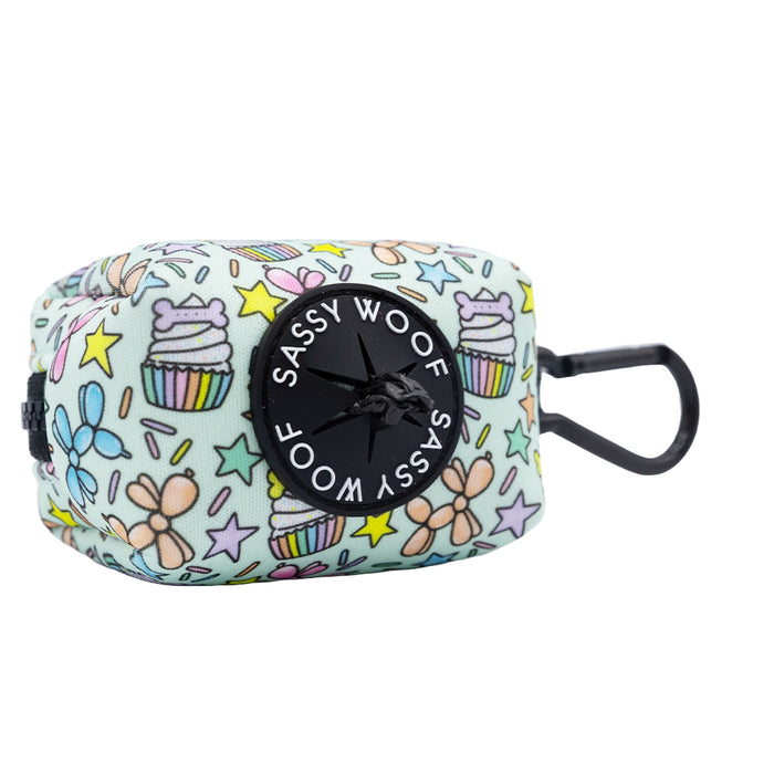 The Sassy Woof Dog Waste Bag Holder - Pup Pup Hooray is a pastel rectangular neoprene accessory with cupcake and flower designs, featuring a black dispenser and clip to attach to your leash or matching harness.