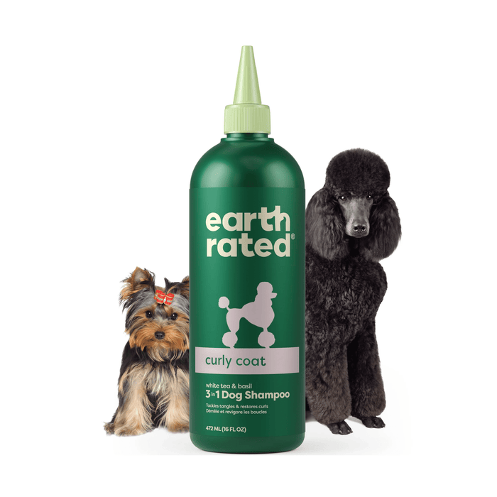 White background with a green bottle of Earth Rated Curly Coat Dog Shampoo, additionally on the bottle is text 'White tea & basil, 3 in 1 Dog Shampoo'. A Yorkshire terrier is pictured on the left and a black standard poodle is on the right of the bottle.