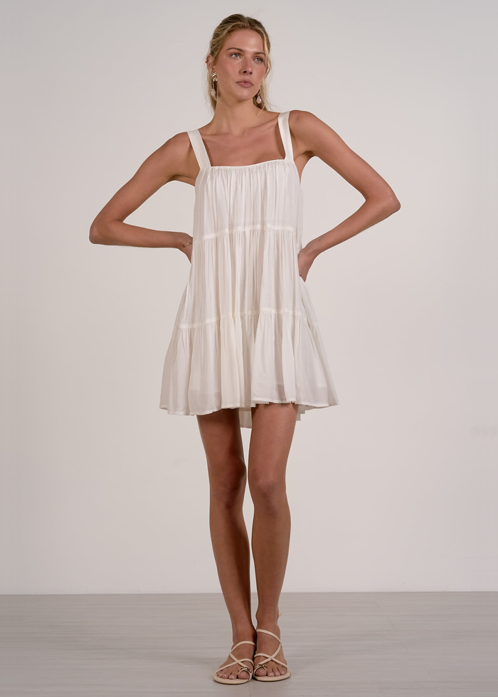 Woman wearing a white tiered mini dress with sandals