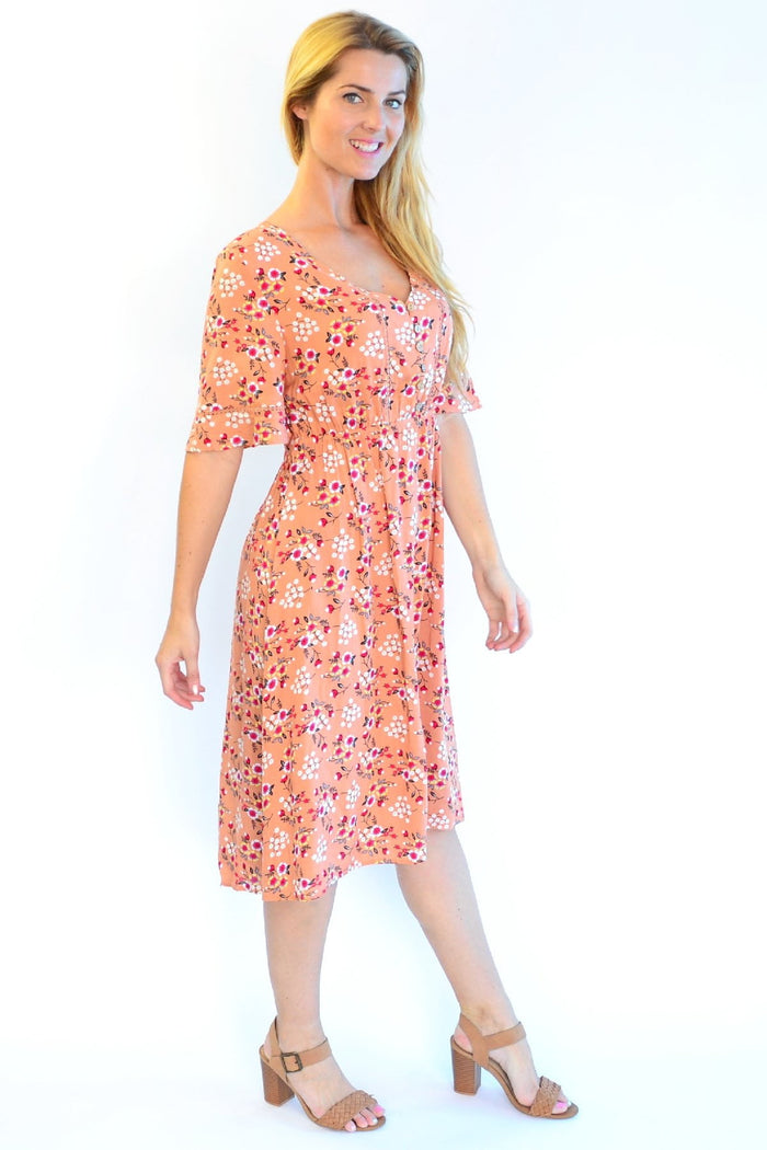Dull orange Zen Garden Field of Flowers tunic dress with floral pattern and relaxed fit, displayed on a hanger.