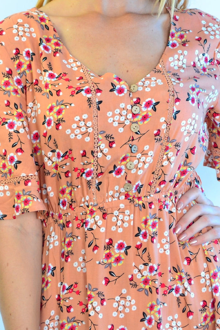 Dull orange Zen Garden Field of Flowers tunic dress with floral pattern, flowing fabric, and relaxed fit displayed on a hanger.
