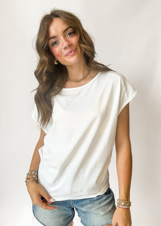 Woman wearing a white t-shirt and denim shorts against a plain background