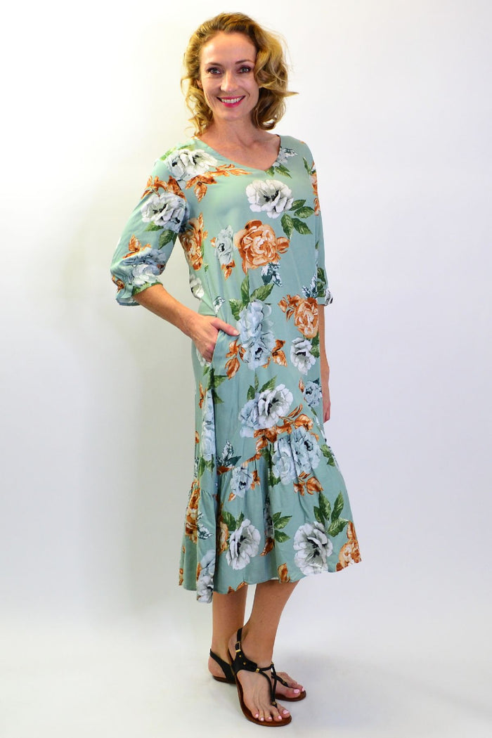 Green Wild Rose tunic slip dress from I Love Tunics, featuring a flowy fabric and floral pattern, displayed on a hanger.