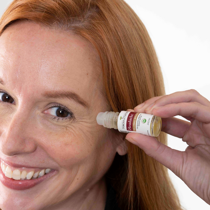 Woman applying Headache roll-on oil to her temple, smiling against a white background