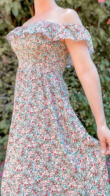 Off-shoulder smocked floral maxi dress with side slit in lush garden setting, feminine and elegant style