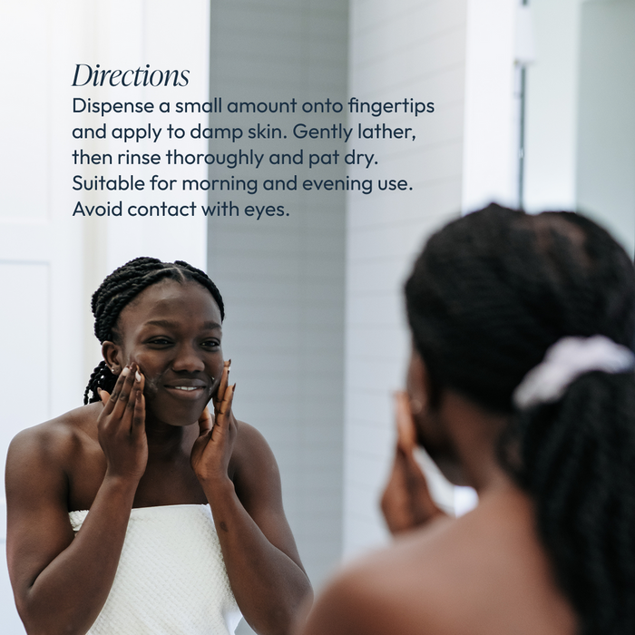Woman with braided hair in a towel applying Lipid Replacing Cleansing Gel | Circadia to her face in front of a bathroom mirror with usage directions visible in the background.