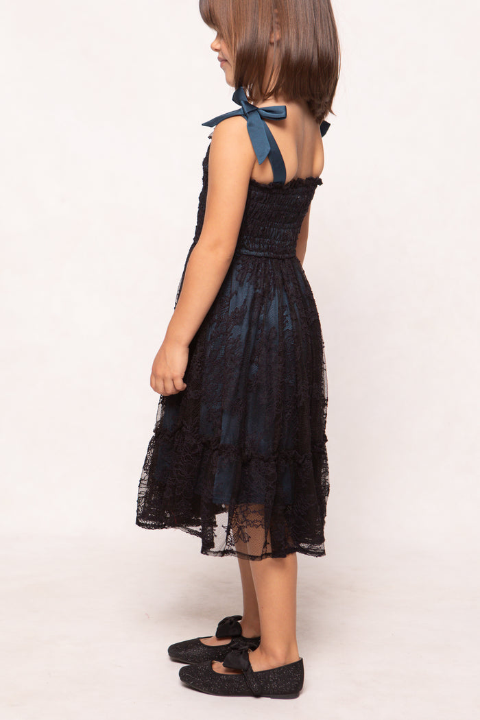 Young girl wearing a black lace dress with a white background