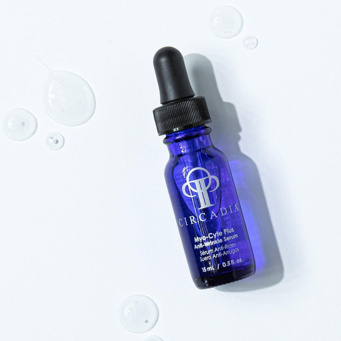 Blue glass dropper bottle of Myo-Cyte Plus | Circadia anti-wrinkle serum with clear serum droplets on a white surface, showcasing skincare product for skin renewal.
