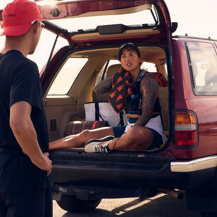 Athlete holding a black and orange patterned Nomadix fitness towel while sitting in the back of an SUV.