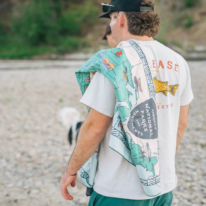 Man carrying a lightweight, recycled Nomadix fitness towel featuring a colorful National Parks map print.