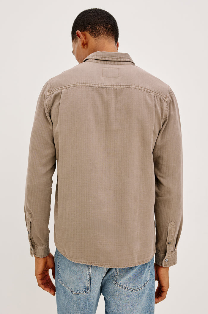 Owens is a long sleeve, collared, button front shirt lightweight cotton, long sleeve, and features a subtle pattern variation on the backside of the fabric in Desert Path colorway. Back view featured on model.