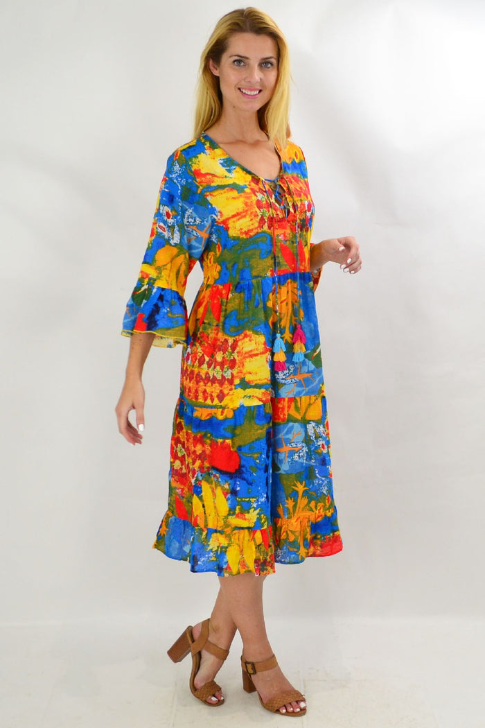 Rainbow Lily tiered tunic dress by Wishstone, featuring colorful layered fabric and flowing silhouette, displayed on a hanger.