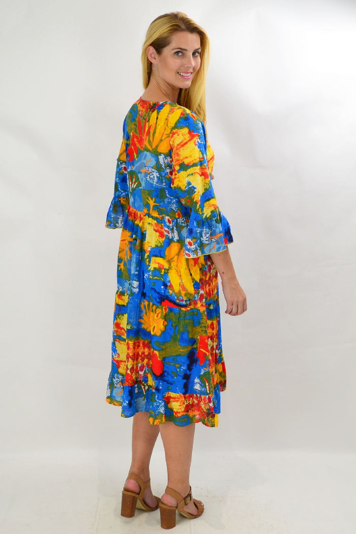 Rainbow Lily tiered tunic dress by Wishstone displayed on a hanger with colorful fabric layers and flowing silhouette.