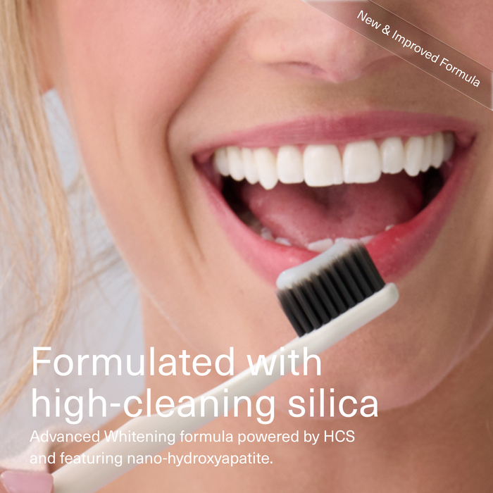 Close-up of a smiling woman's mouth holding a white toothbrush with black bristles, with text reading 'Formulated with high-cleaning silica' and 'New & Improved Formula'.