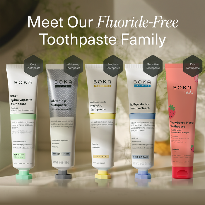 Five Boka toothpaste tubes displayed together with the headline 'Meet Our Fluoride-Free Toothpaste Family' at the top. The tubes include Sea Mint, Whitening Mint, Probiotic, Sensational, and Kids Strawberry Mango flavors, shown against a softly blurred warm indoor background.