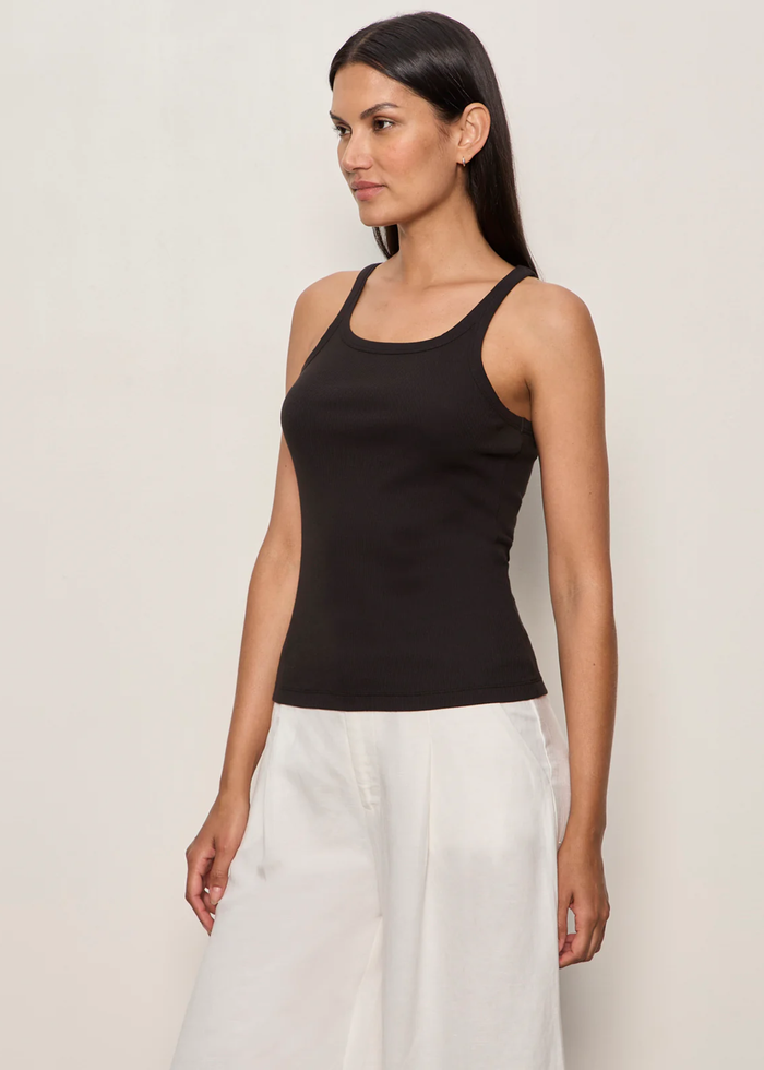 Woman wearing a black tank top with white bottoms and a brown belt