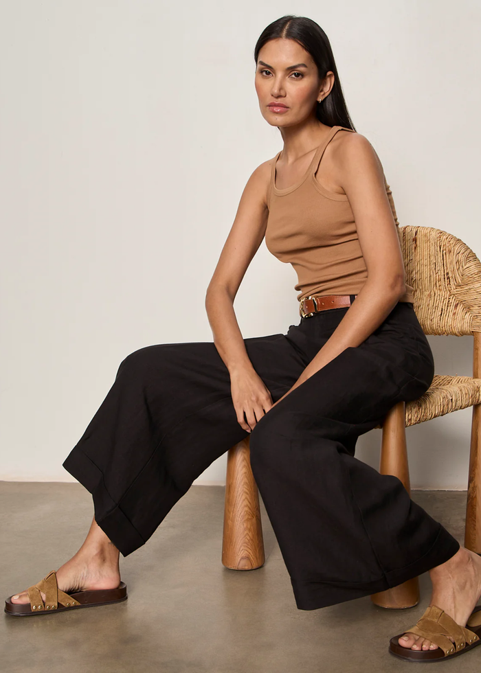 Woman sitting in a chair wearing a brown tank top with black bottoms