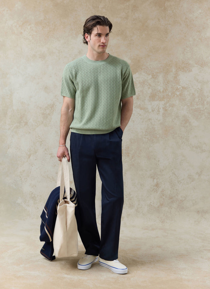 Percival Siena Knitted T-Shirt in pistachio green cotton pointelle, styled with navy trousers and a canvas tote bag.