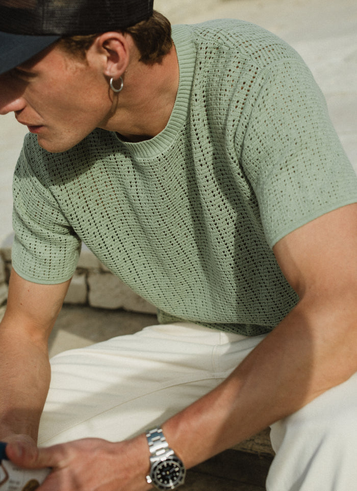 Pistachio green Percival Siena knitted T-shirt in breathable pointelle cotton, worn by a model in an outdoor setting.