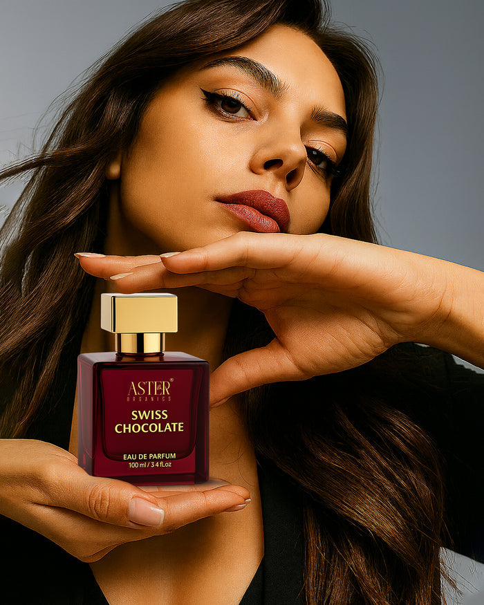Woman holding a bottle of Aster Swiss Chocolate perfume against a neutral background