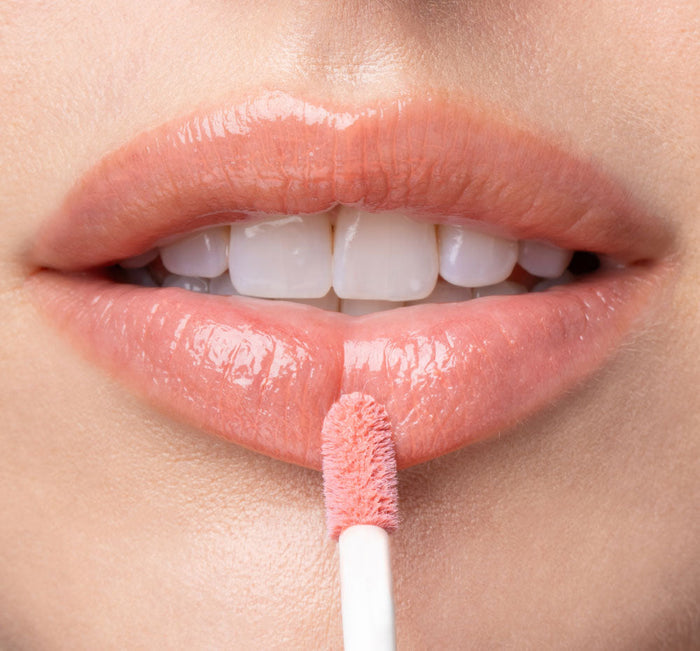 Close-up of lips applying Vitamin Glaze® Oil Infused Lip Gloss – Peach Peony | Farmhouse Fresh with a soft peachy pink shimmer for a glossy, hydrated finish.