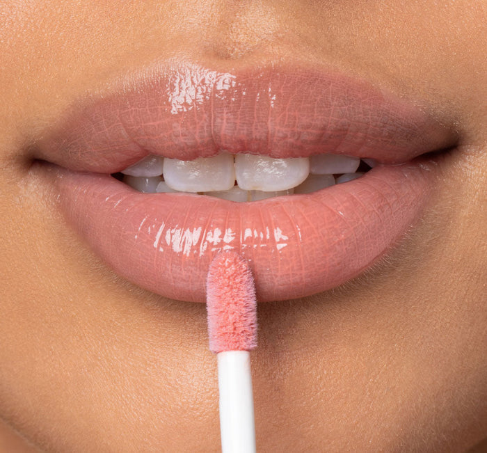 Close-up of lips with a soft peachy pink gloss being applied using a doe-foot applicator, showcasing Vitamin Glaze® Oil Infused Lip Gloss – Peach Peony | Farmhouse Fresh for a shiny, hydrated look.