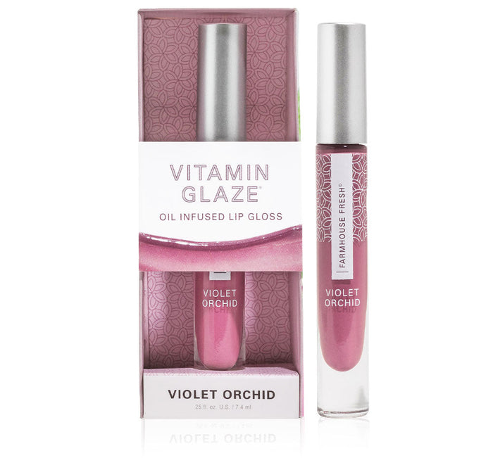 Vitamin Glaze® Oil Infused Lip Gloss – Violet Orchid | Farmhouse Fresh in a sleek tube with metallic cap displayed next to its matching violet orchid patterned box for skincare and wellness.