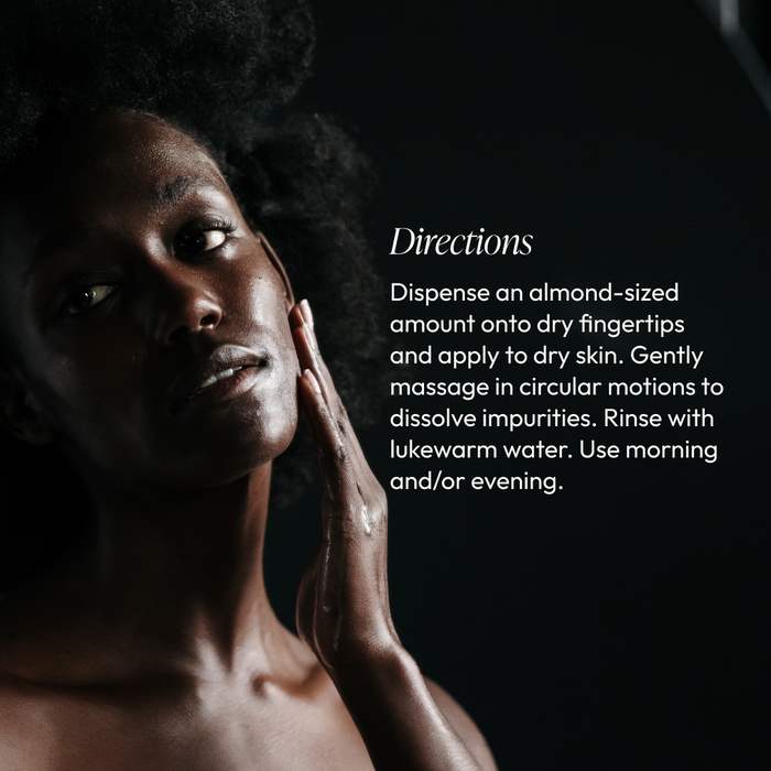 A person with dark skin gently applying Vitamin Veil Cleansing Oil (formerly Vitamin Veil Cleanser) | Circadia to their face, demonstrating skincare application with calm, focused expression.