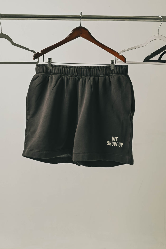 We Show Up Grey shorts on a hanger
